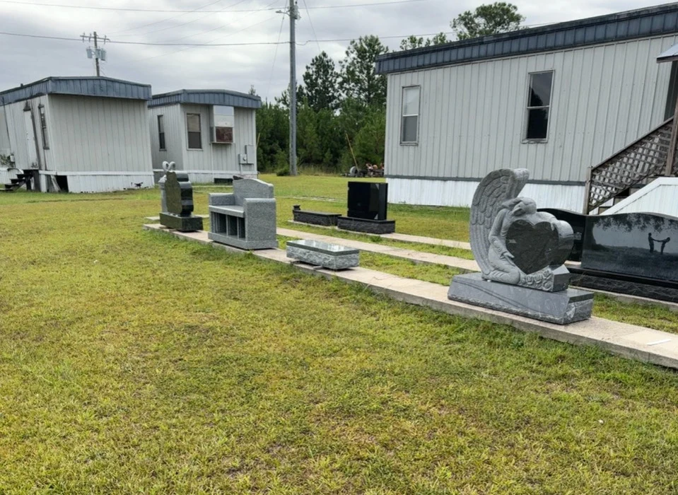 Outdoor monument display at Elberton, including an angel and heart design, granite bench and upright memorials