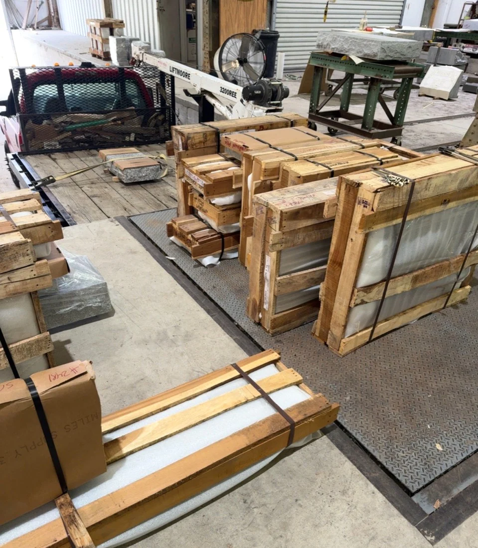 Cushioned wooden monument crates beside a truck in the loading area