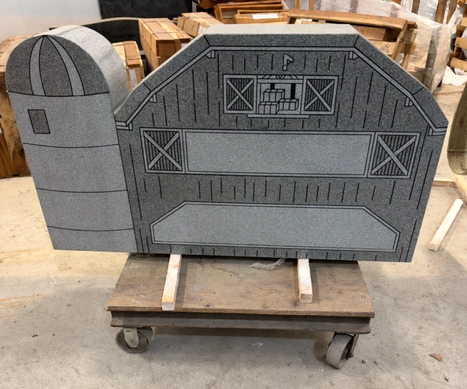 Barn and silo shaped granite monument with sandblasted artwork and blank inscription panels